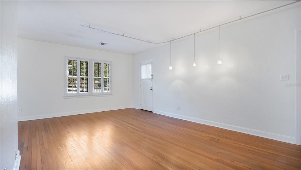 An empty room with hardwood floors, white walls, a window with shutters, and track lighting — 2 W YALE STREET, ORLANDO, FL