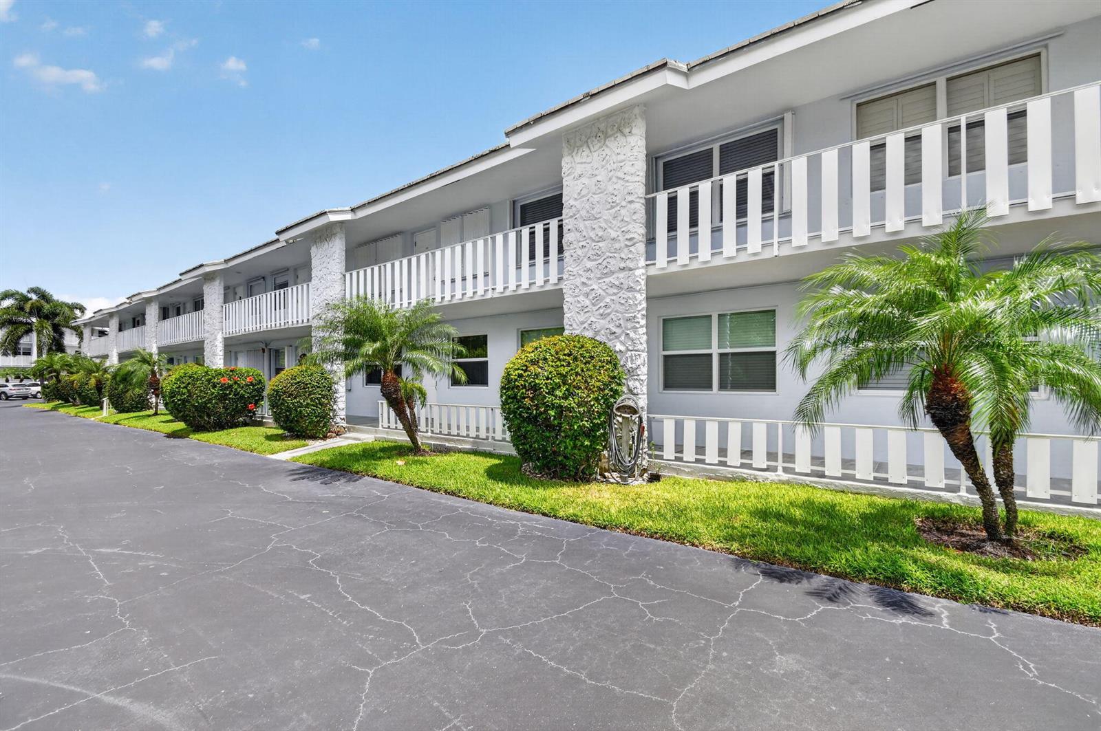 A two-story apartment building with white balconies, textured stone pillars, and palm trees — 5520 N Ocean Boulevard N # 110, Ocean Ridge FL 33435, OCEAN RIDGE, FL