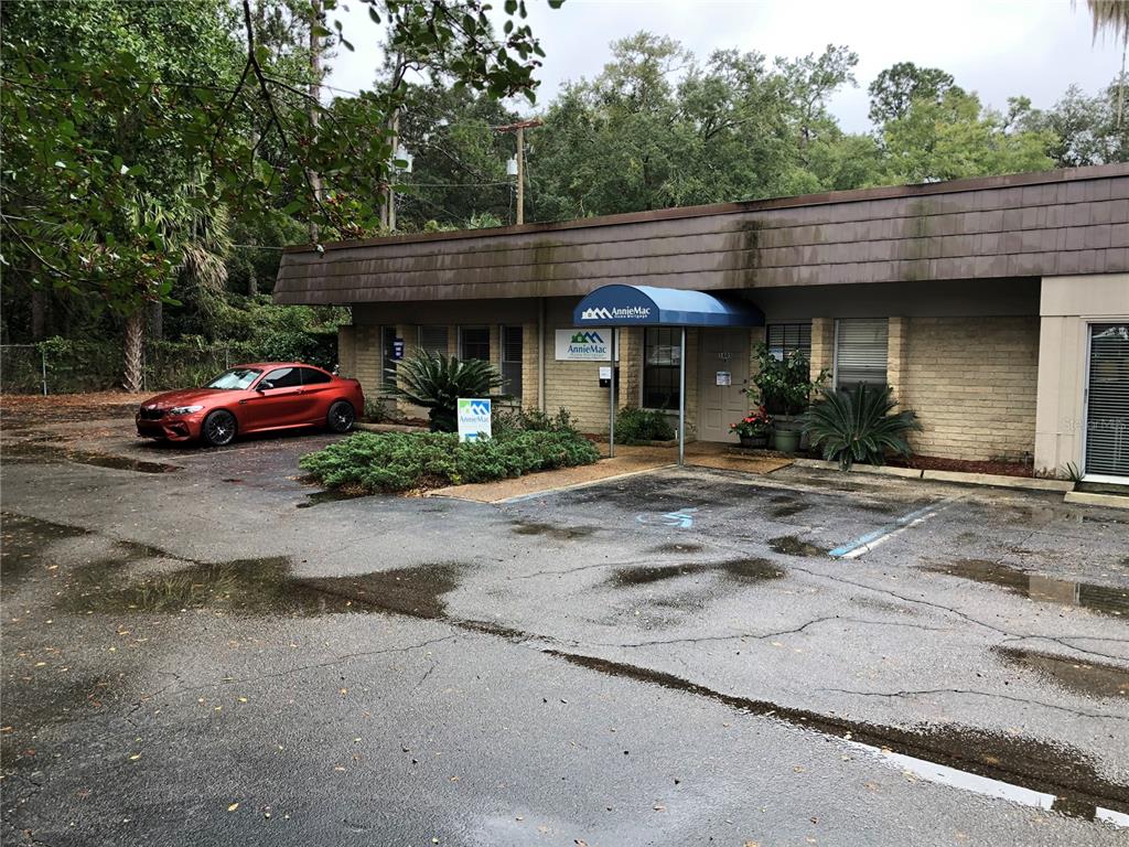 A one-story brick commercial building with a blue awning and a red car parked outside — 1405 NW 13TH STREET UNIT B, GAINESVILLE, FL