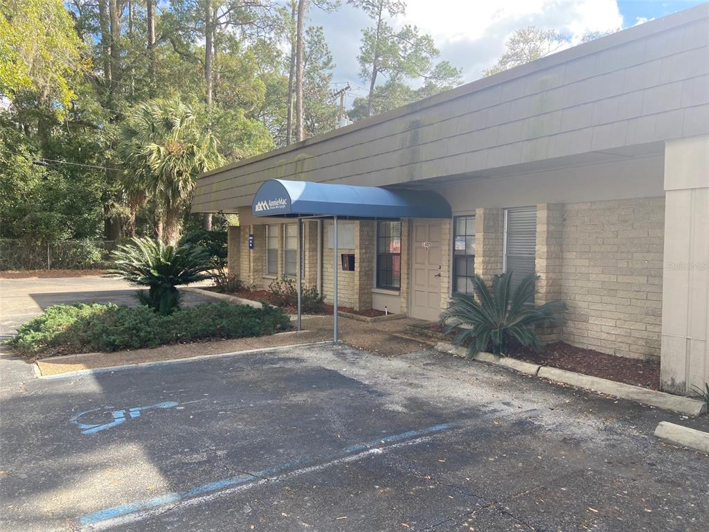 A single-story commercial building with a blue awning over the entrance and a parking lot — 1405 NW 13TH STREET UNIT B, GAINESVILLE, FL
