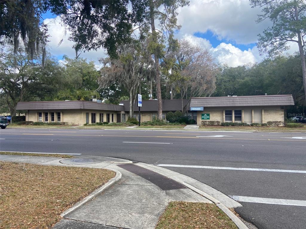 A single-story commercial brick building with a dark brown mansard roof sits along a road — 1405 NW 13TH STREET UNIT B, GAINESVILLE, FL