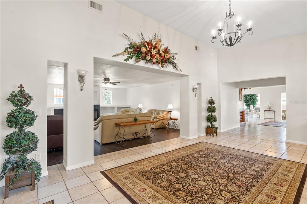 A spacious foyer with tile floors leads into a living room with a vaulted ceiling — 81 N CAROL AVENUE, MASCOTTE, FL