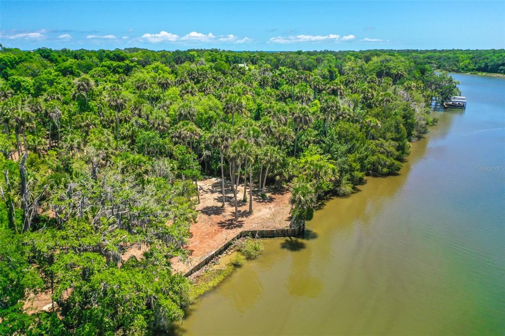 An aerial view shows a cleared waterfront lot surrounded by dense trees and vegetation — 4400 N OCEAN SHORE BOULEVARD, PALM COAST, FL