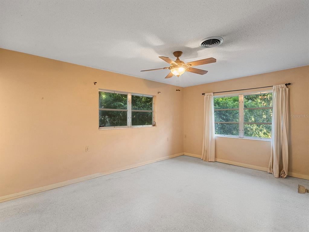 An empty bedroom with beige walls, white carpet, a ceiling fan, and two windows — 2813 TIMBERLAKE DRIVE, ORLANDO, FL