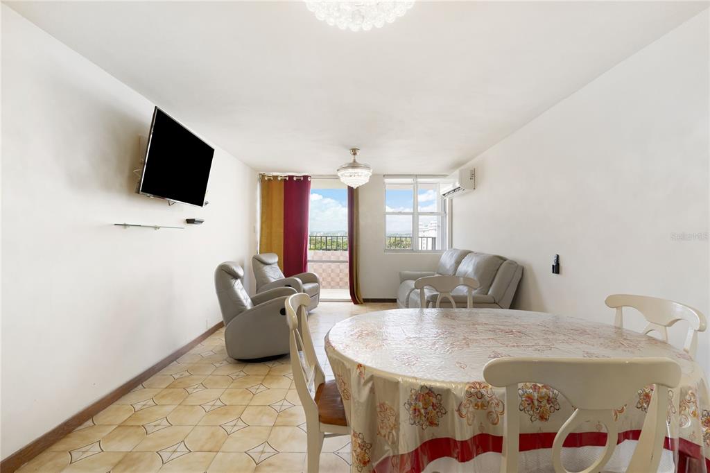 A living and dining area with tile floors, a television, and a balcony view — 801 CANGREJO ARRIBA UNIT 801 A, CAROLINA, PR