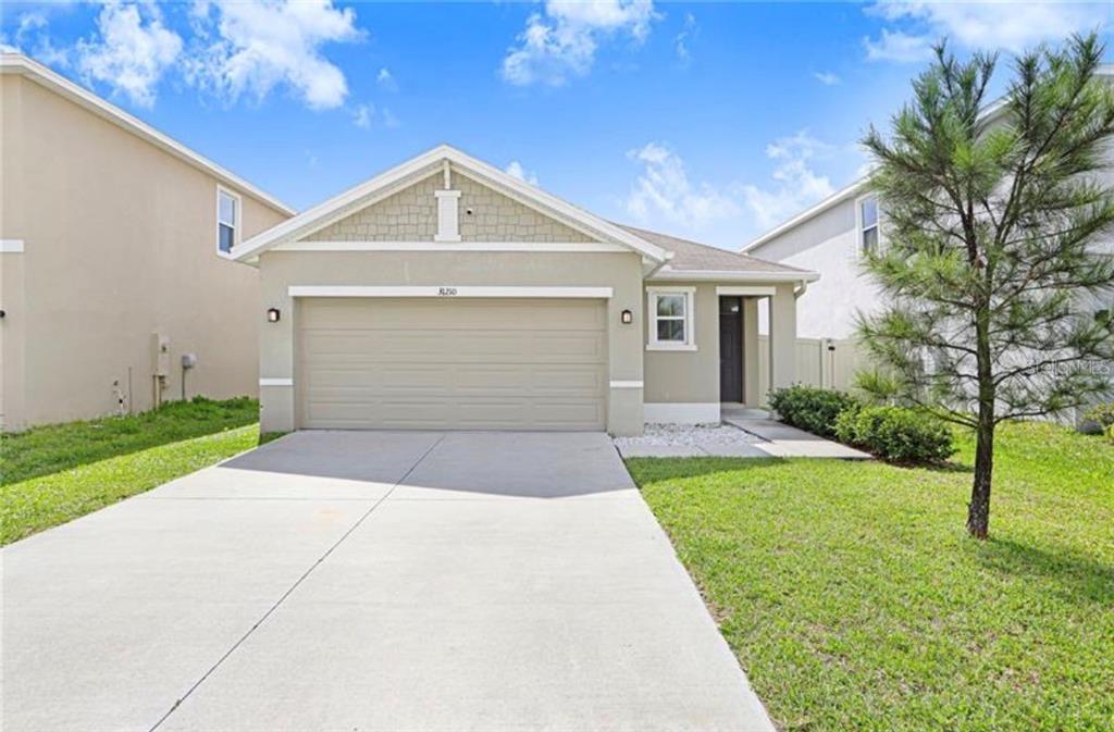 A single-story suburban house with a beige stucco exterior, a two-car garage, and a driveway — 31210 PENNY SURF LOOP, WESLEY CHAPEL, FL