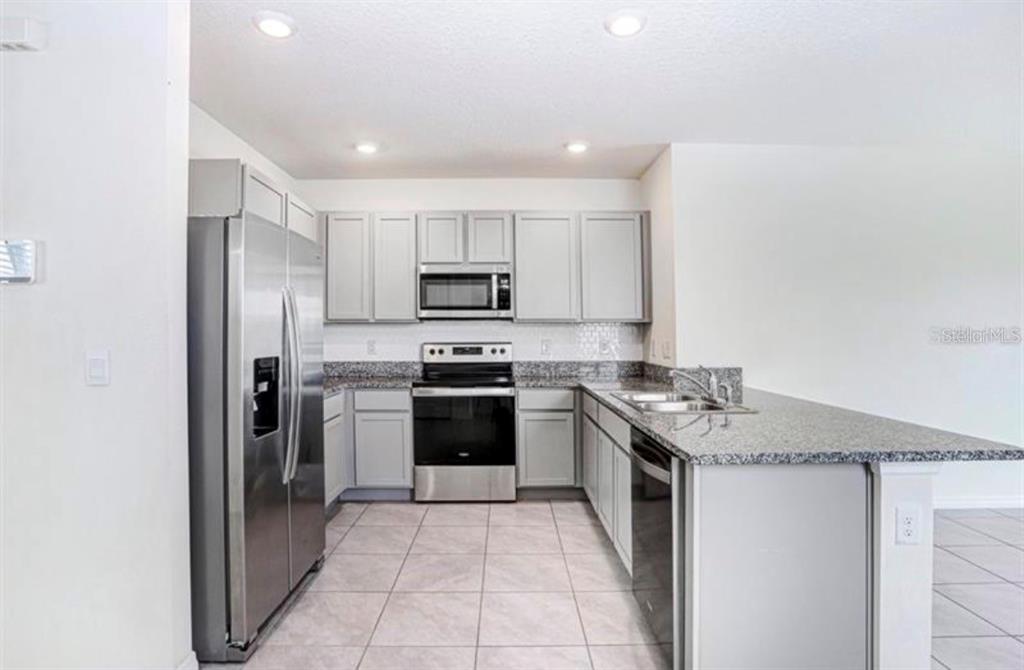 A kitchen features light gray cabinets, stainless steel appliances, and granite countertops — 31210 PENNY SURF LOOP, WESLEY CHAPEL, FL