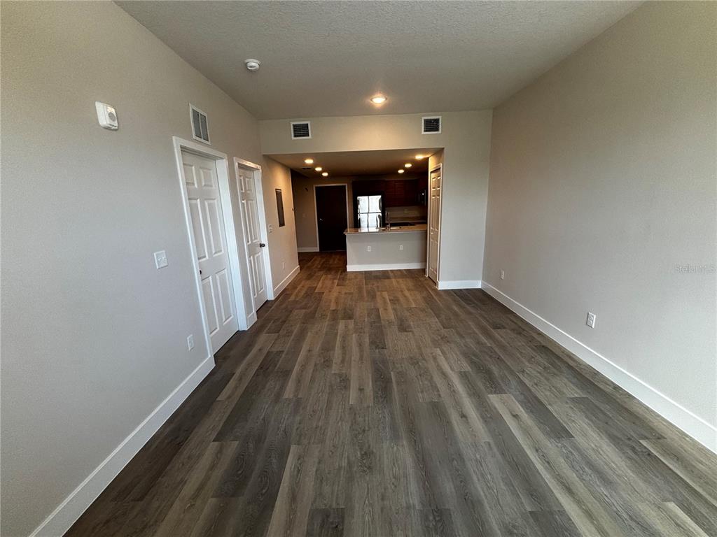 A living area with wood-look flooring leads to an open kitchen with a breakfast bar — 4424 S TEXAS AVENUE UNIT 210, ORLANDO, FL