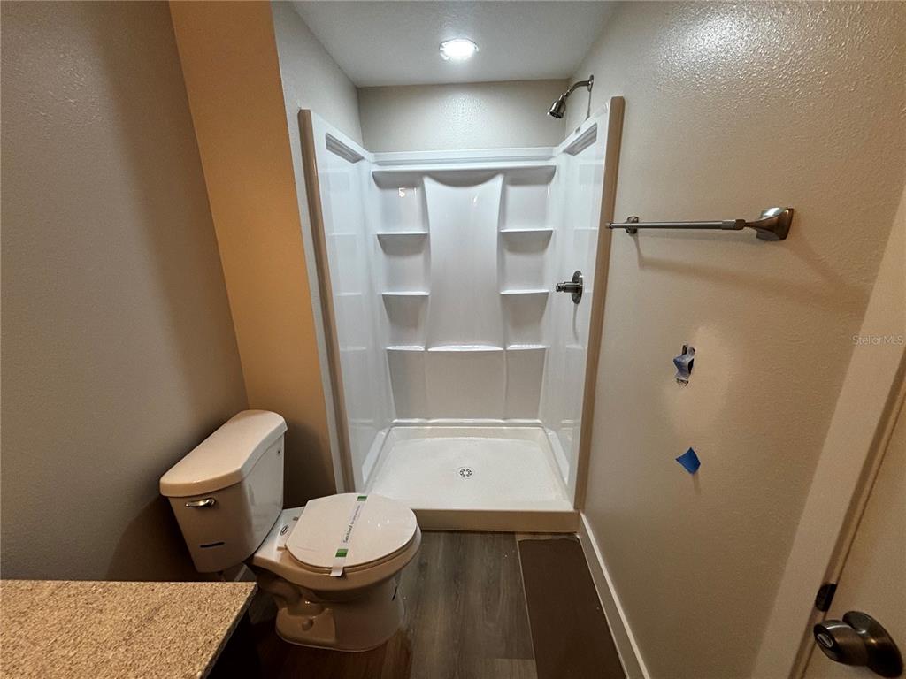 A bathroom features a white shower stall, a toilet, and a towel bar on the wall — 4424 S TEXAS AVENUE UNIT 210, ORLANDO, FL