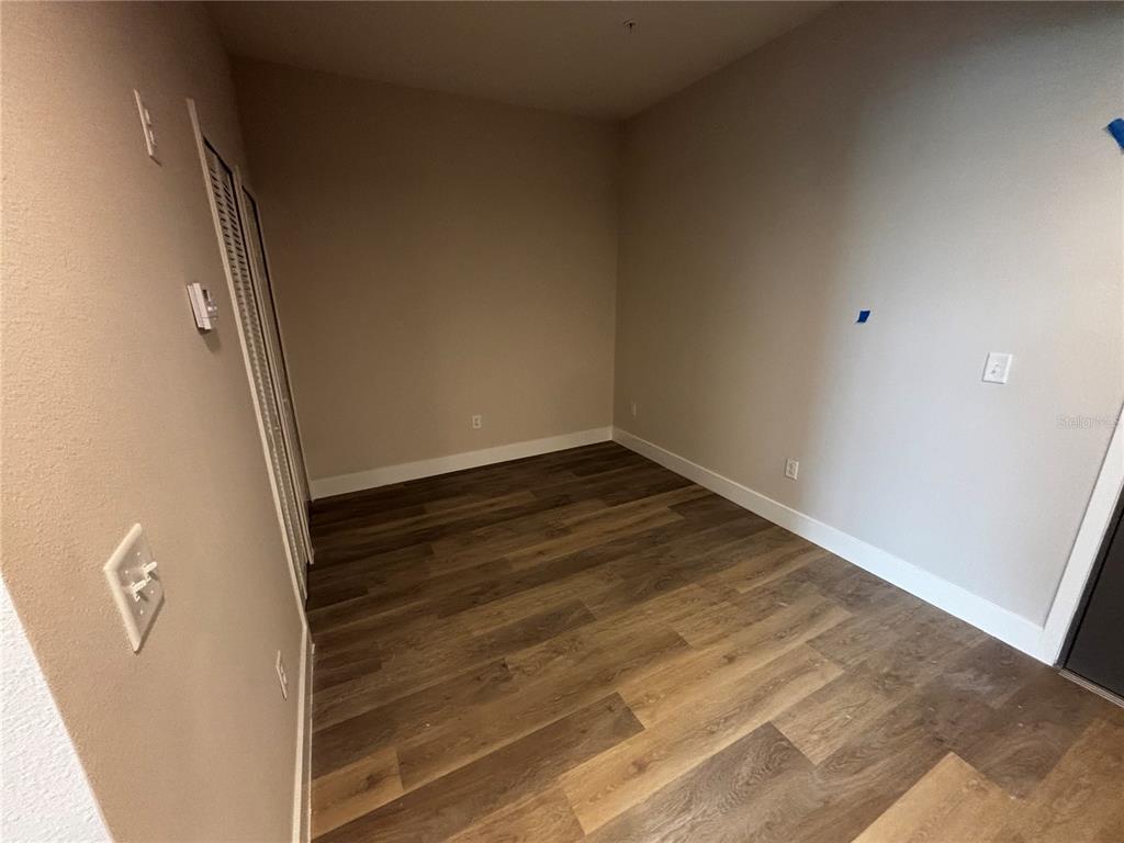 An empty room features wood-look flooring, light-colored walls, and a white closet door — 4424 S TEXAS AVENUE UNIT 210, ORLANDO, FL
