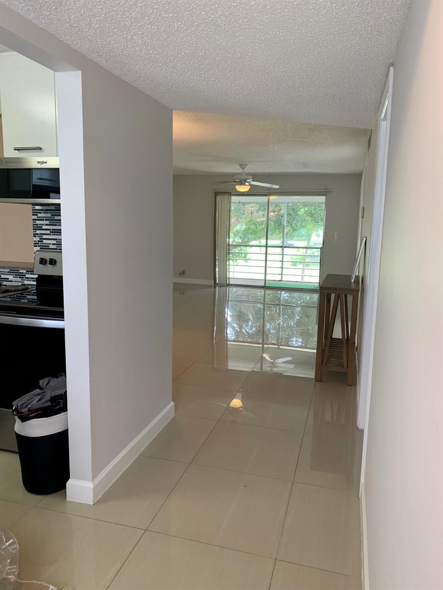 A view from a kitchen hallway looking toward a living area with large sliding doors — 2500 Fiore Way # a, Delray Beach FL 33445, DELRAY BEACH, FL