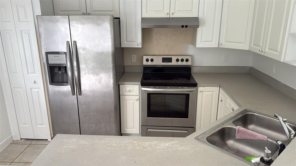 A kitchen features stainless steel appliances, white cabinetry, and gray countertops — 2930 GRAYTON STREET, DELTONA, FL
