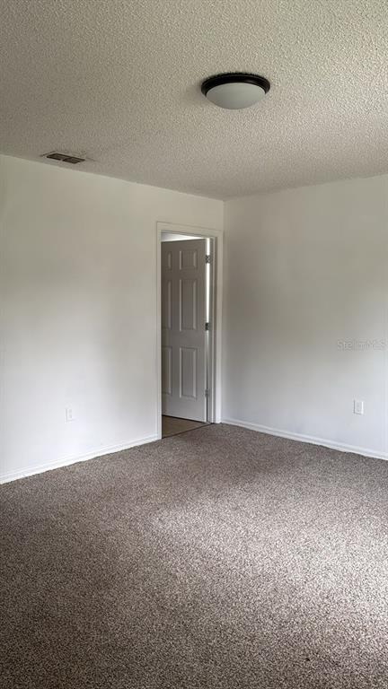 An empty room with beige carpet, white walls, a ceiling light, and an open doorway — 2930 GRAYTON STREET, DELTONA, FL