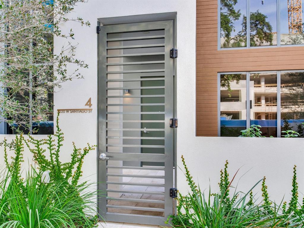 A gray slatted metal gate stands at the entrance of a modern white building — 3020 W SANTIAGO STREET UNIT 4, TAMPA, FL