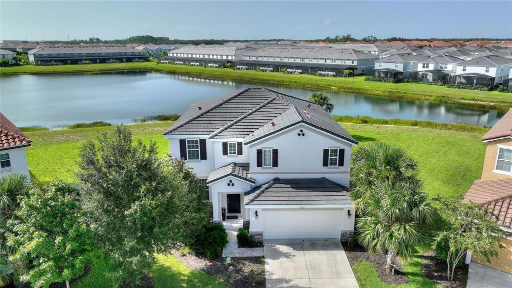 An aerial view of a two-story suburban house with a gray tile roof and pond — 5427 OAKGRAIN COURT, DAVENPORT, FL