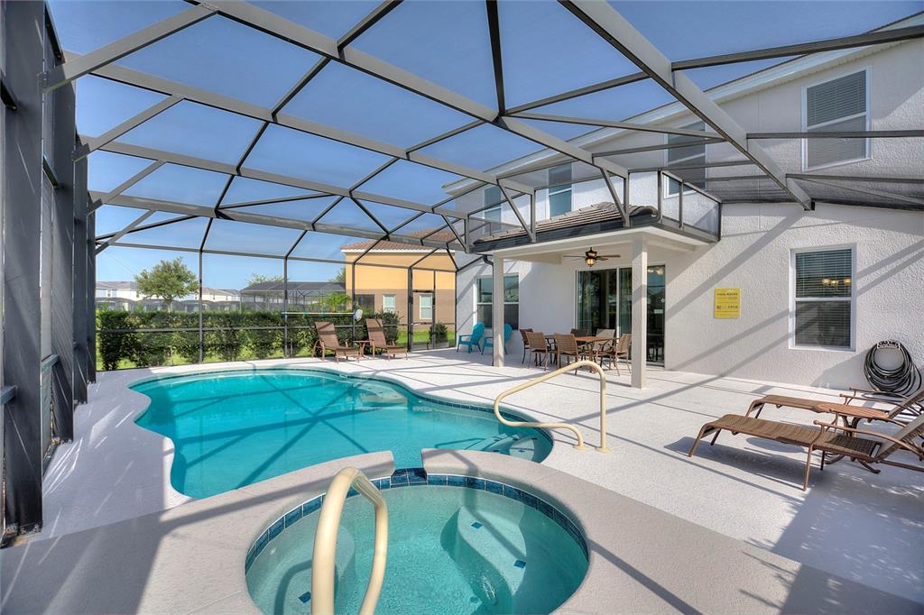 A screened-in patio features a swimming pool, a hot tub, and outdoor dining furniture — 5427 OAKGRAIN COURT, DAVENPORT, FL