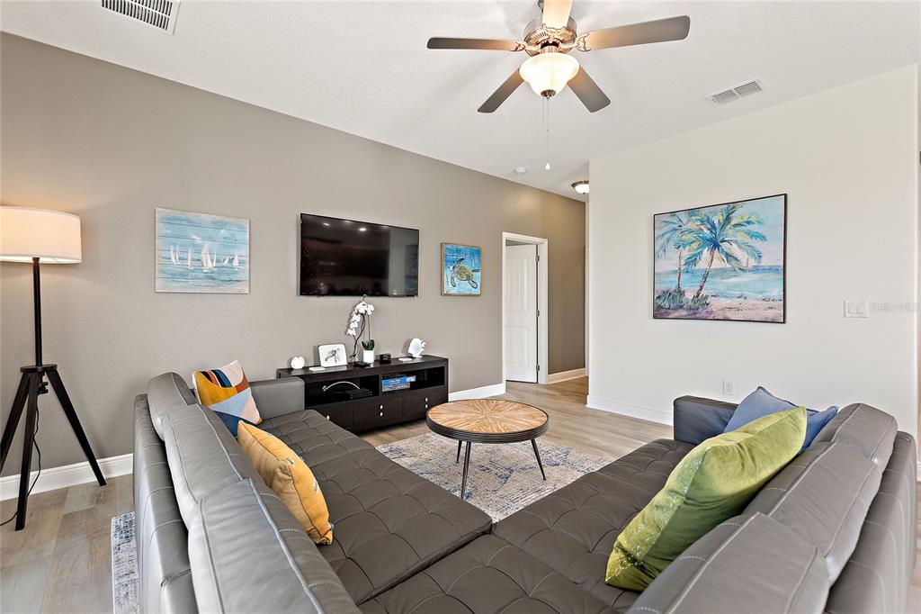A living room features a grey sectional sofa, a television, and a ceiling fan — 5427 OAKGRAIN COURT, DAVENPORT, FL