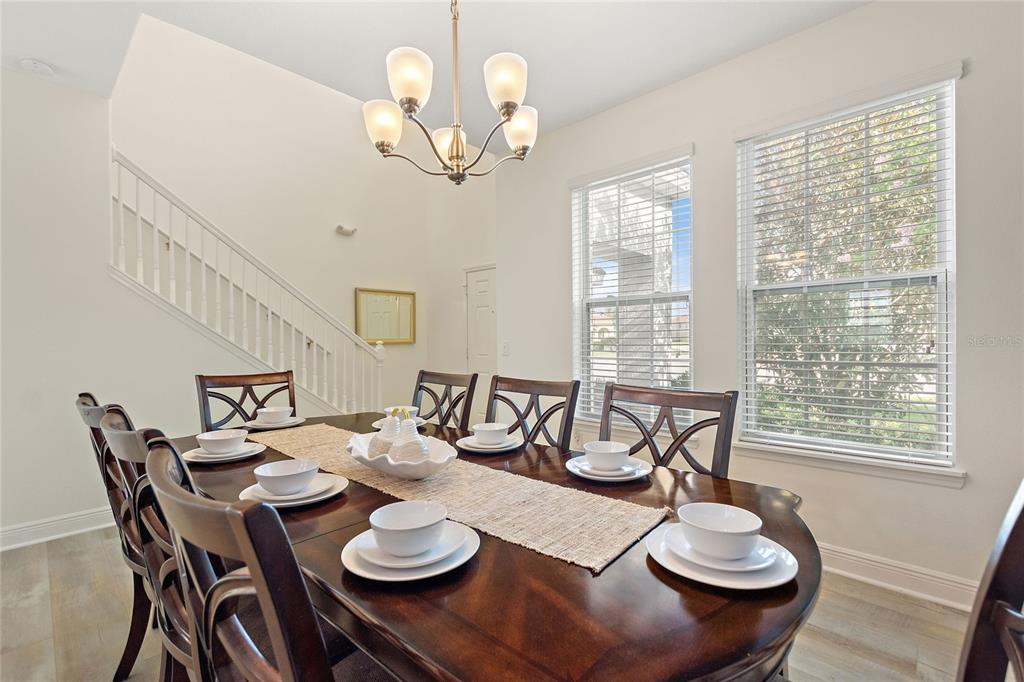 A dining room features a dark wood table, six chairs, and a chandelier — 5427 OAKGRAIN COURT, DAVENPORT, FL