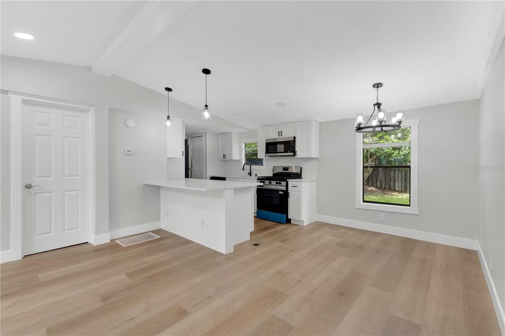A kitchen with white cabinets, a peninsula, and light wood flooring in an open space — 1706 CHARLESTON LANE, ST CLOUD, FL