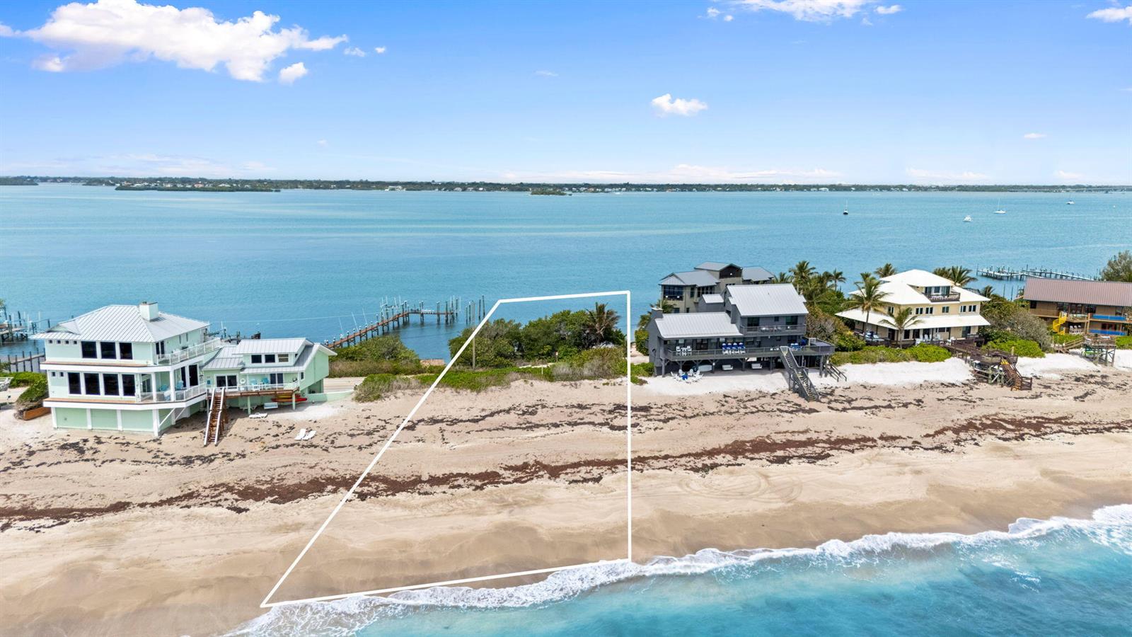An aerial view shows a vacant beachfront lot outlined in white between two coastal houses — 918 SE Macarthur Boulevard, Stuart FL 34996, STUART, FL