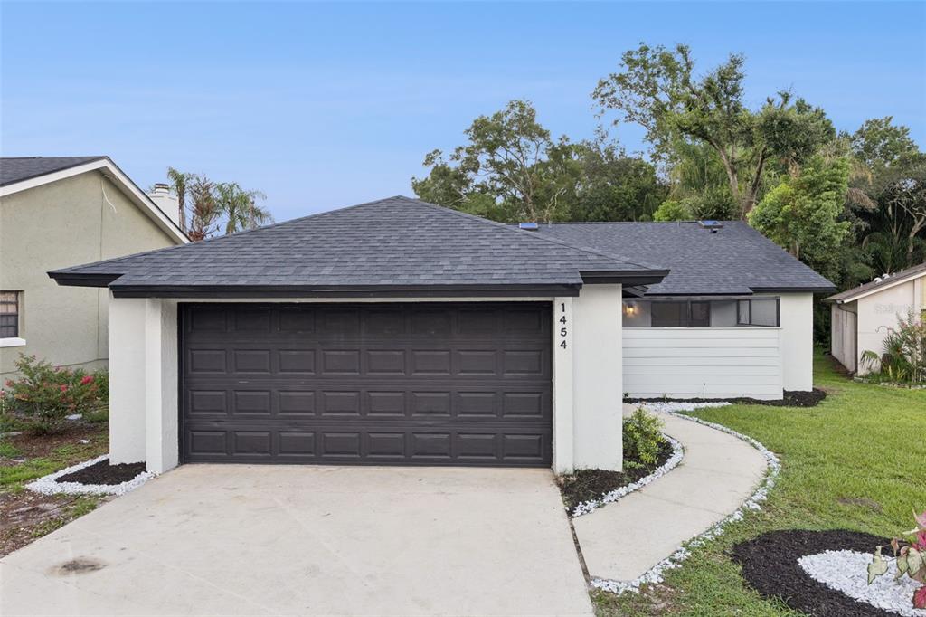 A single-story house with a white stucco exterior, dark roof, and a front-facing garage — 1454 KING COURT, WINTER SPRINGS, FL