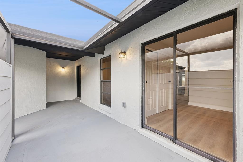 A covered patio with a gray concrete floor, white stucco walls, and sliding glass doors — 1454 KING COURT, WINTER SPRINGS, FL