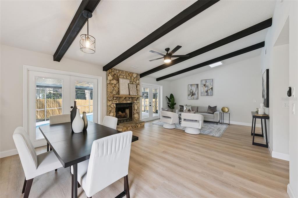 An open-concept living and dining area features vaulted ceilings with dark beams and stone fireplace — 1454 KING COURT, WINTER SPRINGS, FL