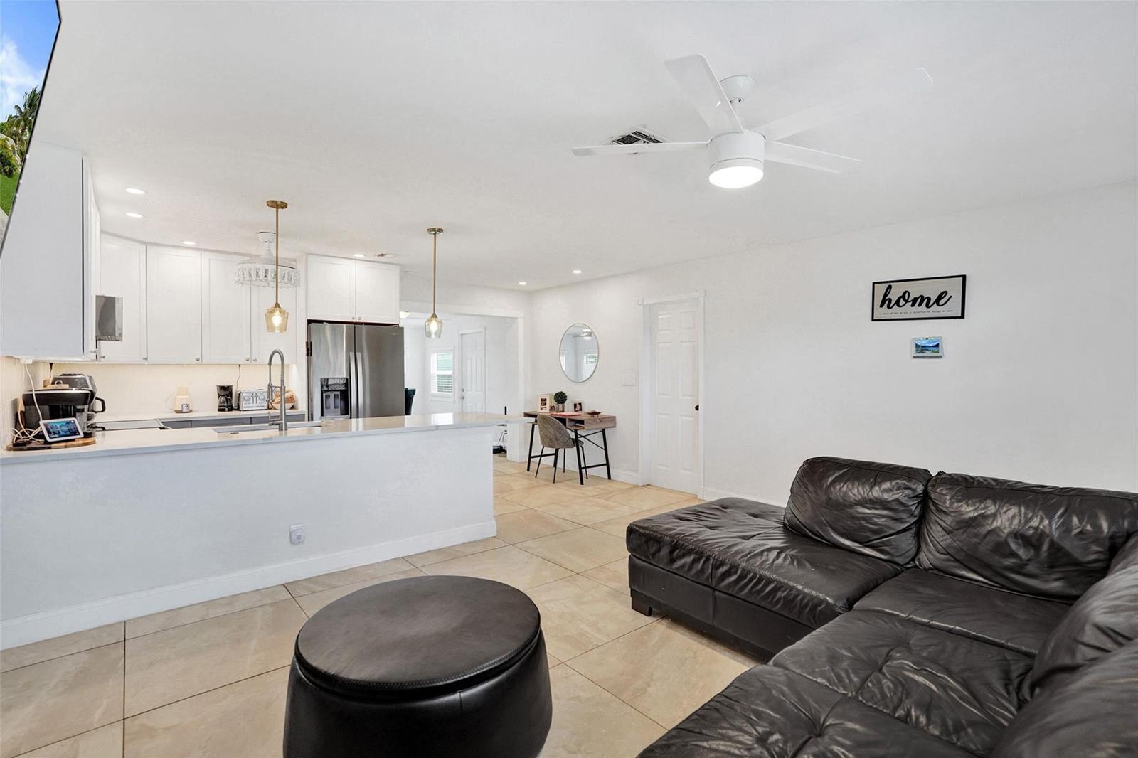 An open-concept living room and kitchen feature white cabinetry, tile flooring, and a leather sectional — 6298 NW 15th Street, Margate FL 33063, MARGATE, FL