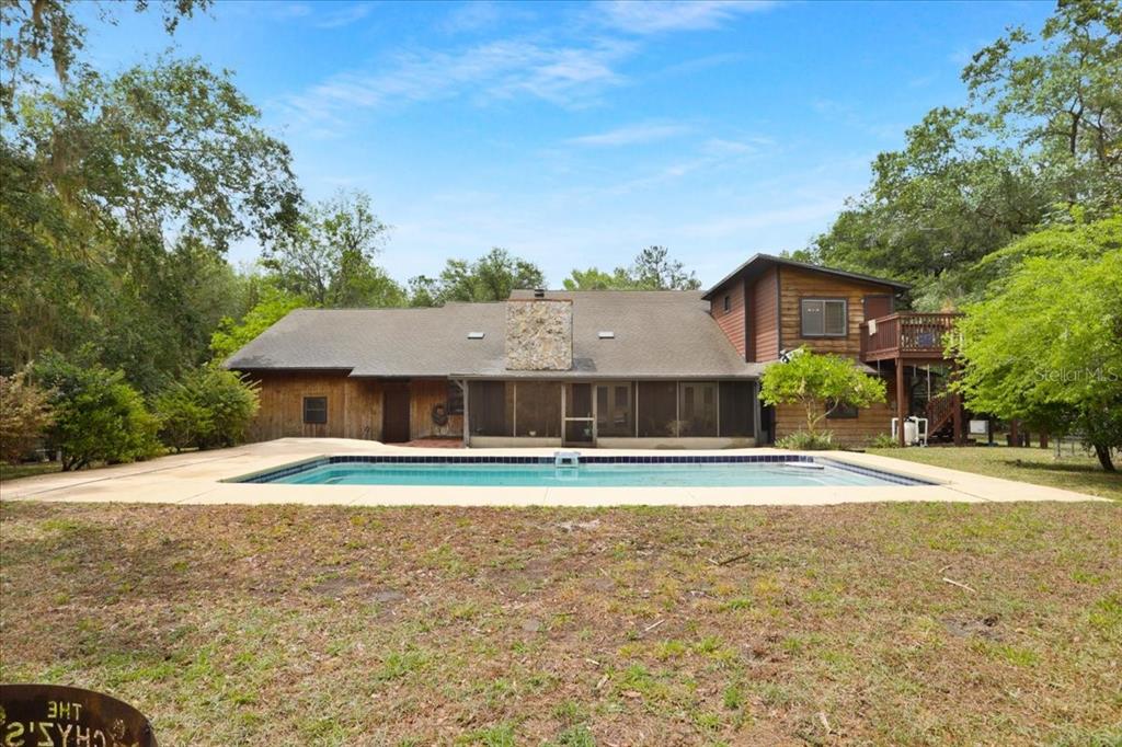 A two-story house with wood siding, a stone base, and an attached garage — 22731 NW 91ST COURT ROAD, MICANOPY, FL