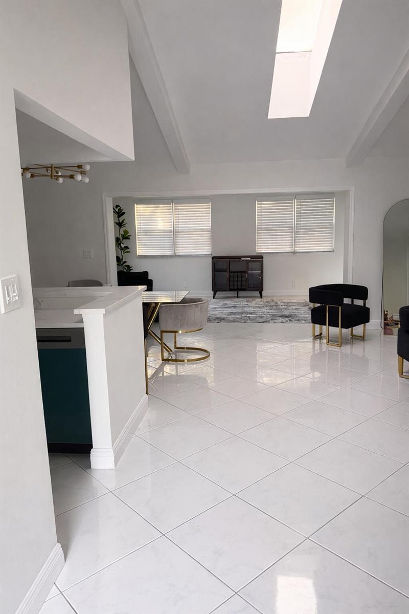 A bright, open-concept living and dining area features white tile flooring and vaulted ceilings — 9940 Liberty Road, Boca Raton FL 33434, BOCA RATON, FL