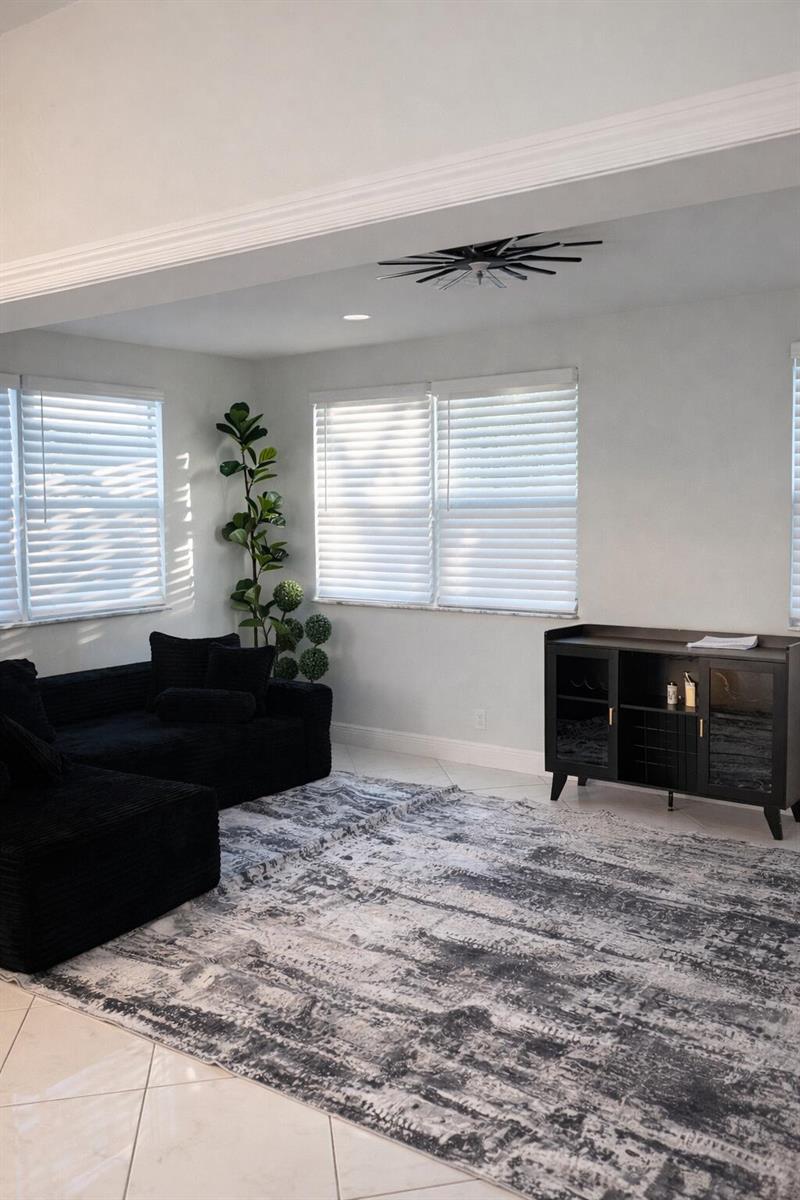 A living room features a black sectional sofa, a patterned area rug, and a black cabinet — 9940 Liberty Road, Boca Raton FL 33434, BOCA RATON, FL