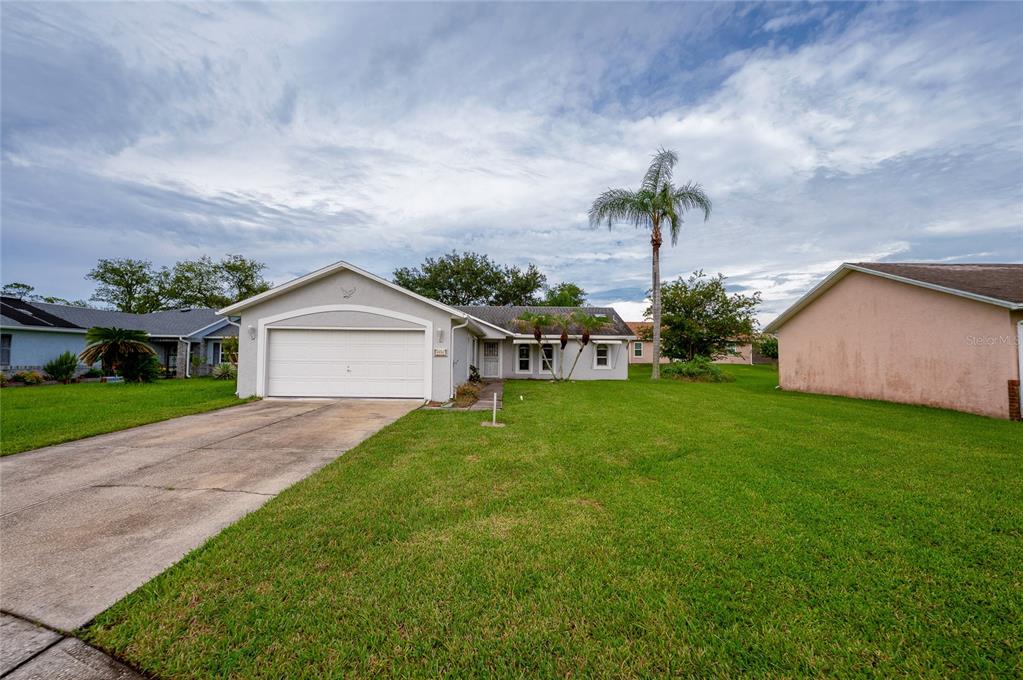 A single-story house with a white garage, light-colored stucco exterior, and a large front lawn — 5450 LANDIS AVENUE, PORT ORANGE, FL