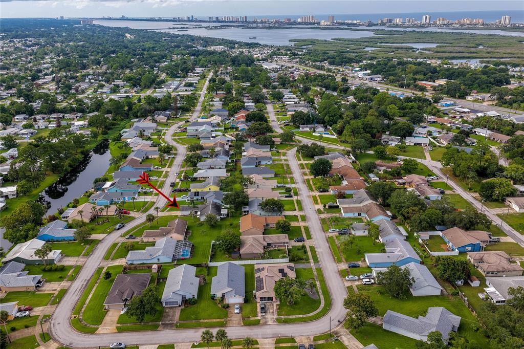 An aerial view shows a suburban neighborhood with single-family homes, green lawns, and paved streets — 5450 LANDIS AVENUE, PORT ORANGE, FL