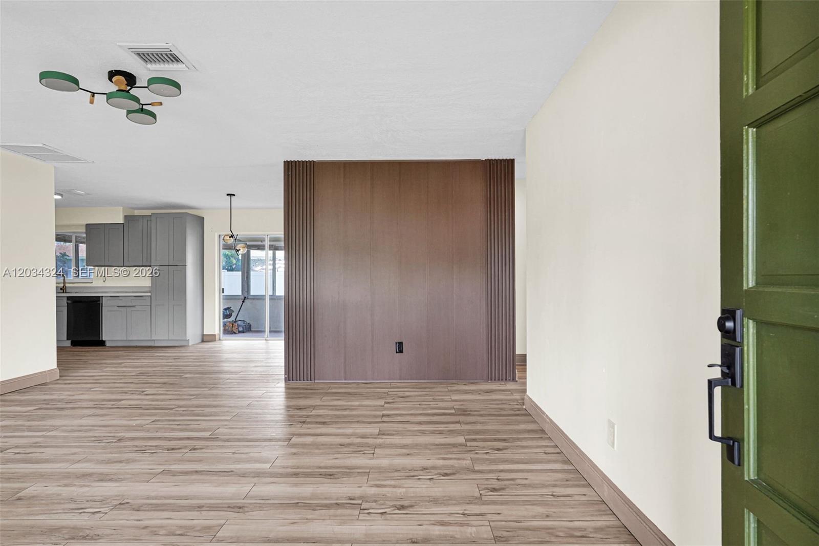 An open living area features wood-look flooring, a central wood-paneled wall, and an adjacent kitchen — 3140 NE 9th Ter, Pompano Beach FL 33064, POMPANO BEACH, FL