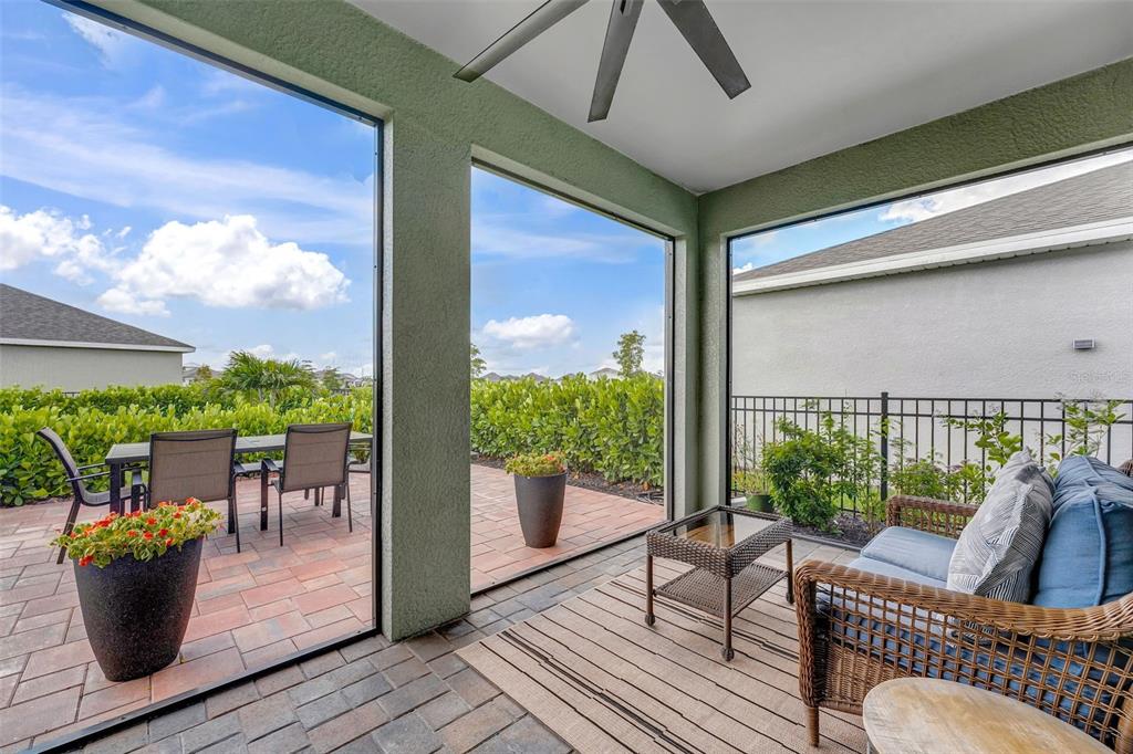 A screened-in patio features a paved floor, outdoor furniture, and views of a landscaped yard — 16711 ELKHORN CORAL DRIVE, NORTH FORT MYERS, FL