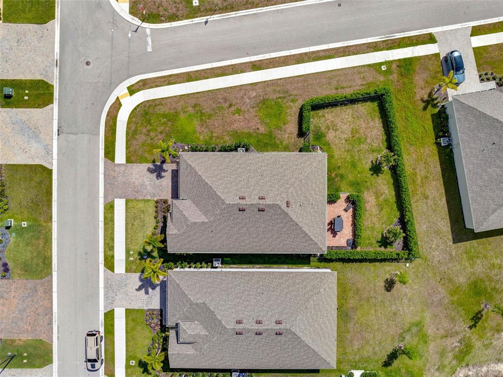 An aerial view shows two adjacent houses with paved driveways and a fenced backyard — 16711 ELKHORN CORAL DRIVE, NORTH FORT MYERS, FL