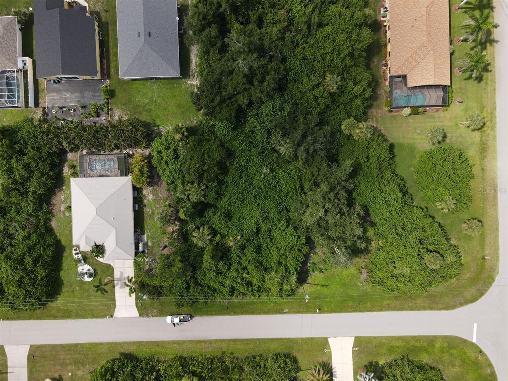 An aerial view shows a vacant, wooded lot situated between two residential houses — 392 ALBATROSS ROAD, ROTONDA WEST, FL