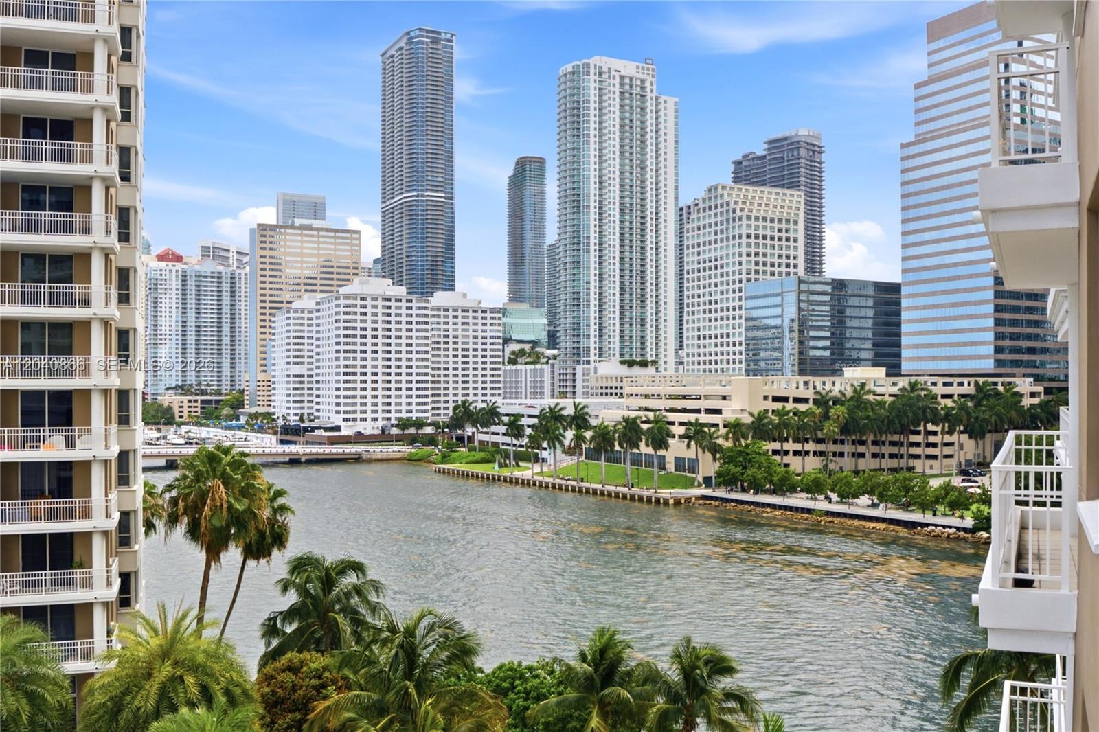 A view from a balcony overlooking a river, palm trees, and a city skyline — 801 Brickell Key Blvd # 707, Miami FL 33131, MIAMI, FL