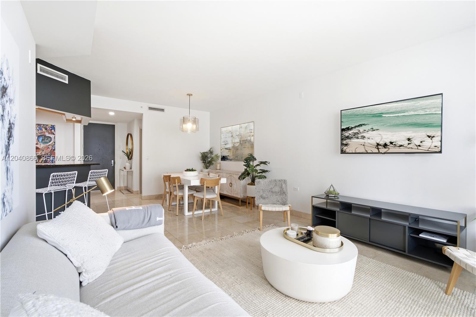 A bright living and dining area features a white sofa, coffee table, and modern decor — 801 Brickell Key Blvd # 707, Miami FL 33131, MIAMI, FL