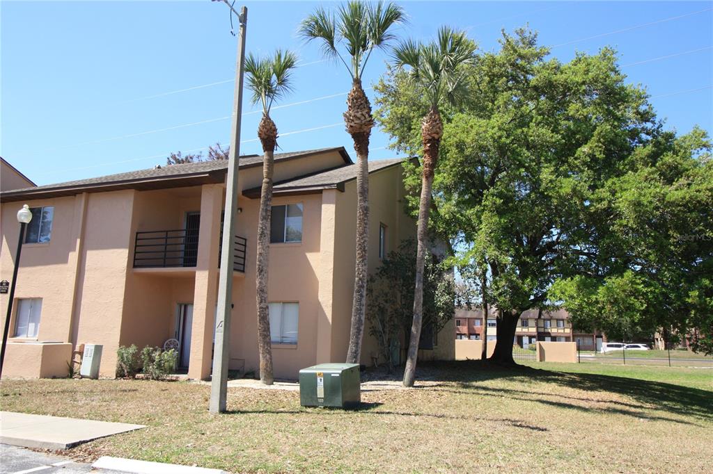 A two-story tan apartment building with palm trees and a large tree in the yard — 5208 VIA HACIENDA CIRCLE UNIT A201, ORLANDO, FL