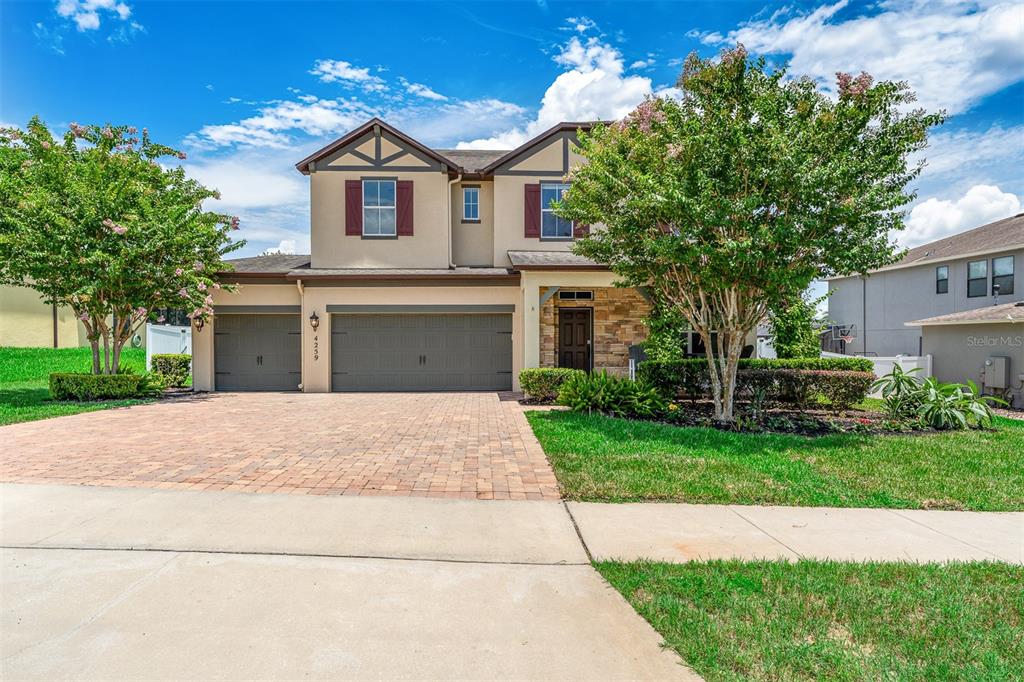 A two-story house with a brick driveway, three-car garage, and a stone-accented entryway — 4259 CAPLOCK STREET, CLERMONT, FL