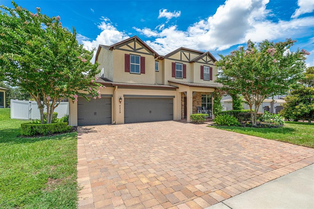 A two-story house with a paved driveway, three-car garage, and two flowering trees — 4259 CAPLOCK STREET, CLERMONT, FL