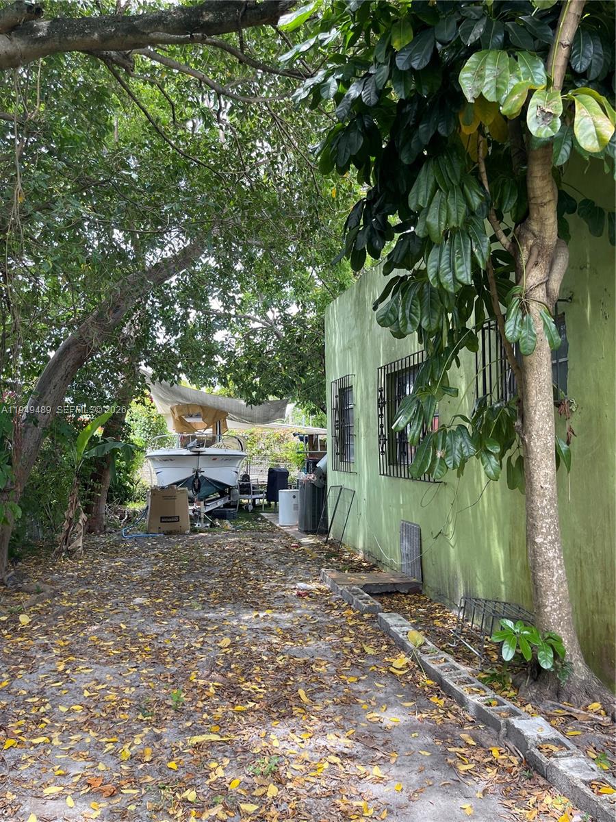 A side view of a green house exterior with a boat parked in the yard — 1120 NW 31st St, Miami FL 33127, MIAMI, FL