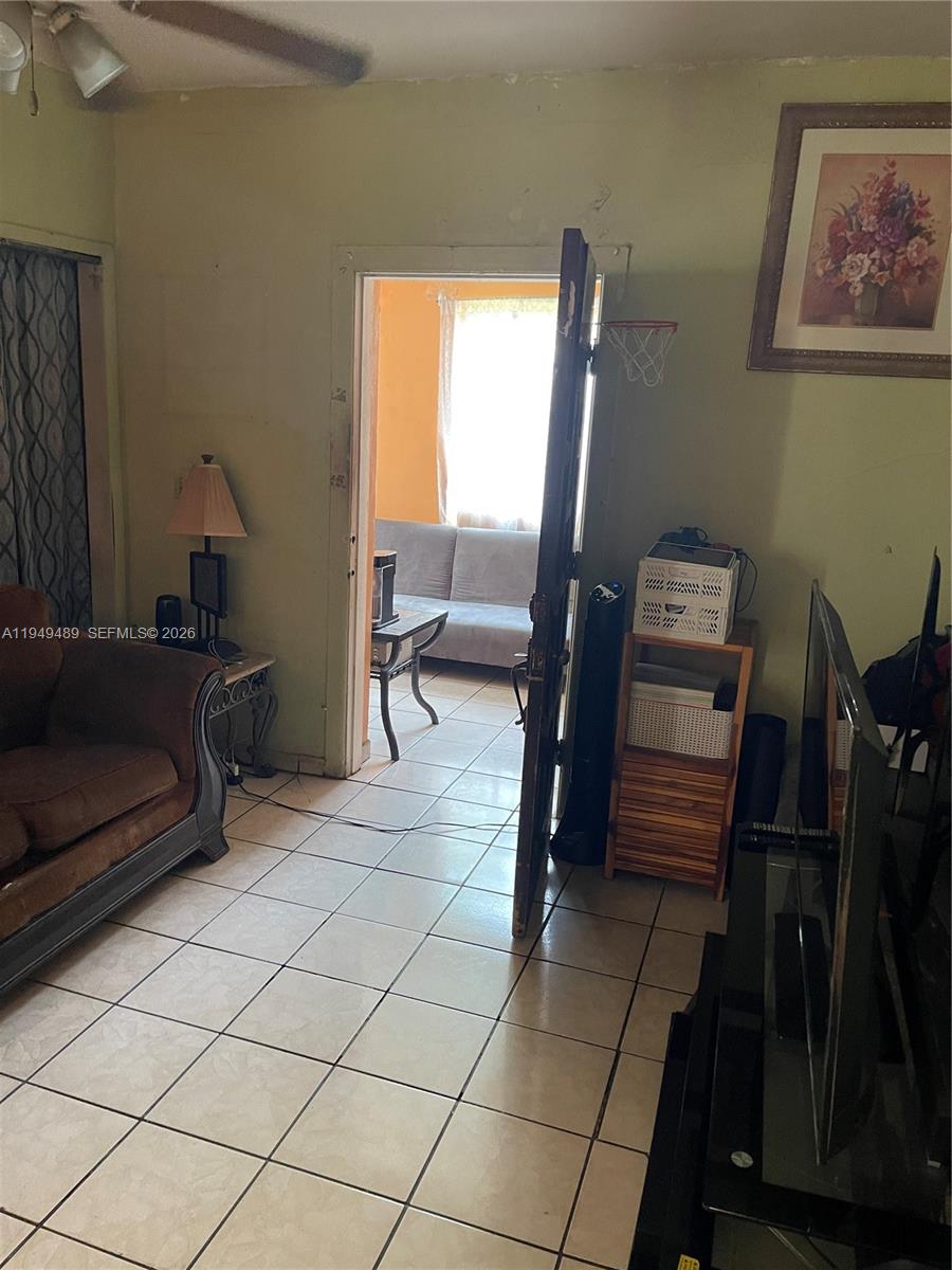 A living room with tiled floors, a brown sofa, and an open doorway to another room — 1120 NW 31st St, Miami FL 33127, MIAMI, FL