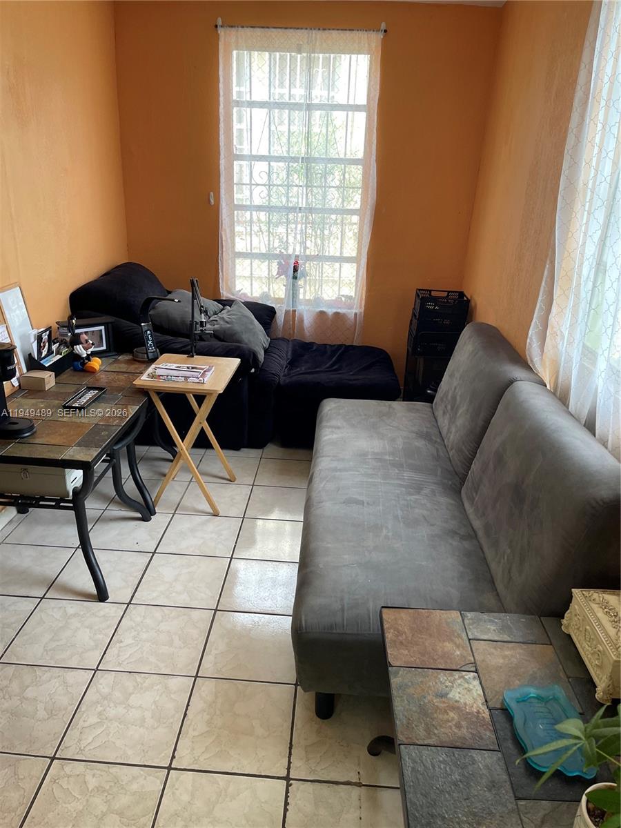 A small room features tile flooring, orange walls, a desk, and two sofas — 1120 NW 31st St, Miami FL 33127, MIAMI, FL