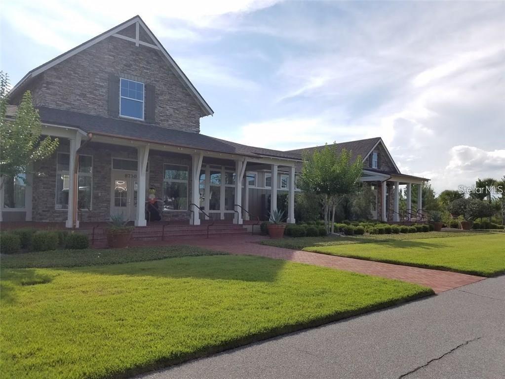 A stone-clad building with a covered porch and brick walkway sits beside a grassy lawn — 8026 CORKFIELD AVE, ORLANDO, FL