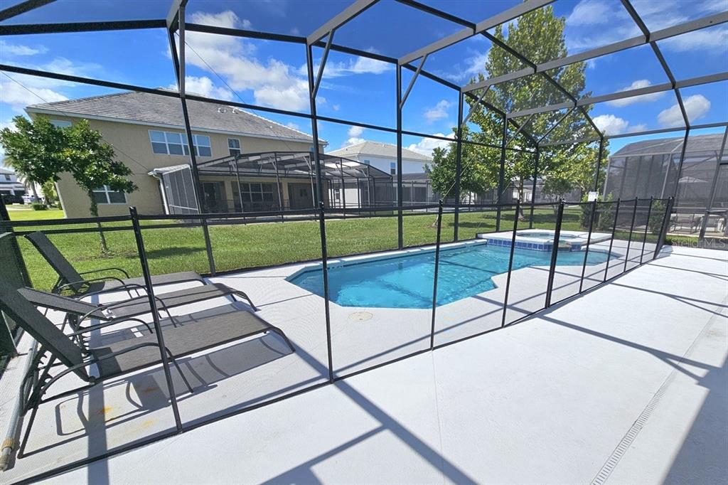 A fenced swimming pool and spa are enclosed within a screened lanai with lounge chairs — 3810 OAKVILLE AVENUE, KISSIMMEE, FL