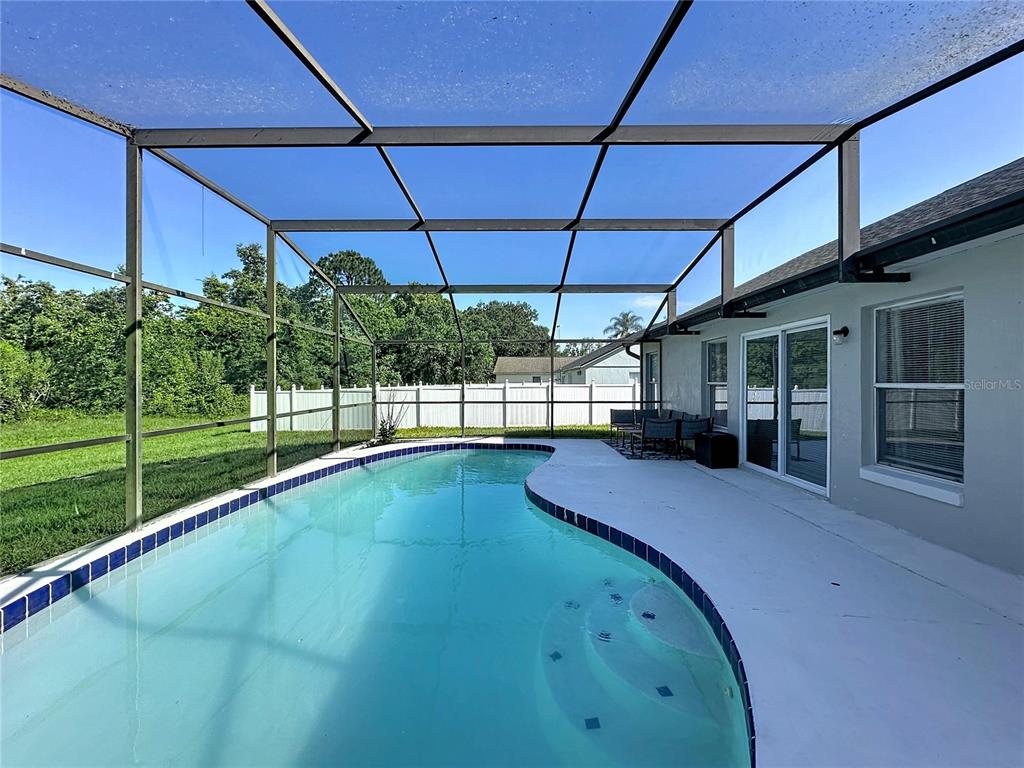 A swimming pool with a blue tiled border sits inside a screened-in patio enclosure — 240 SUNRISE RD, DAVENPORT, FL