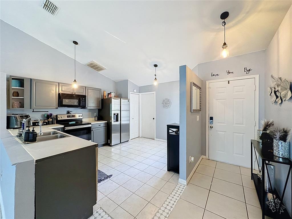 A kitchen with gray cabinets and stainless steel appliances opens into an entryway with tile flooring — 240 SUNRISE RD, DAVENPORT, FL