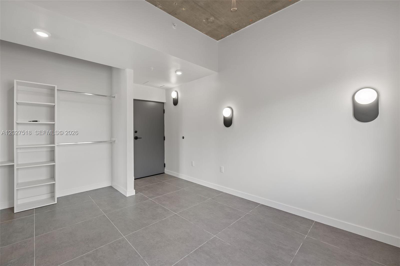 A room with gray tile flooring, white walls, a closet area, and modern wall sconces — 315 NW 32 ST # 305, Miami FL 33127, MIAMI, FL